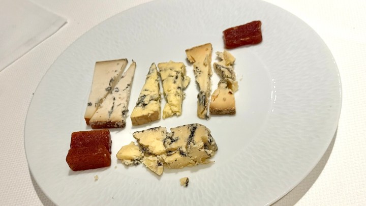 A plate featuring a selection of blue cheeses and a red jelly, arranged neatly.