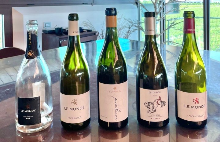 A selection of wines from the Le Monde winery displayed on a table, including a bottle of Pinot Nero rosé, Pinot Bianco, and various white wines labeled with the Le Monde logo.