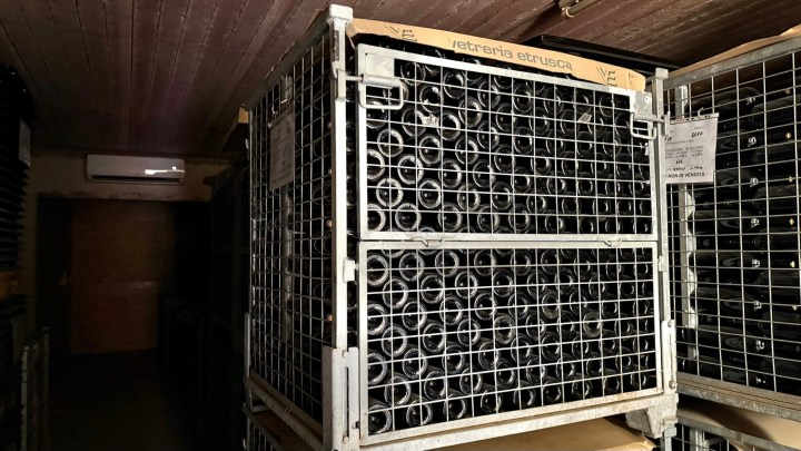 A wine storage rack filled with bottles, located in a dimly lit cellar.