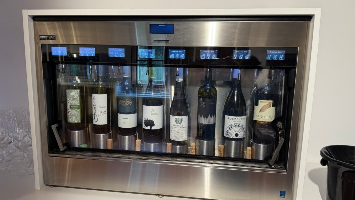 A wine dispensing machine showcasing various bottles of wine with labeled selections and automated dispensers.