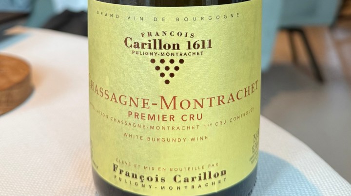 Close-up of a bottle of Chassagne-Montrachet Premier Cru white Burgundy wine from François Carillon, showcasing the label with details about the wine.