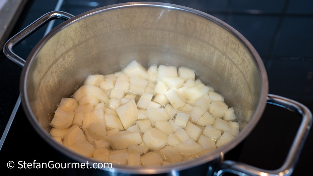 A pot containing diced parsley root cooking in water, creating a base for a puree.