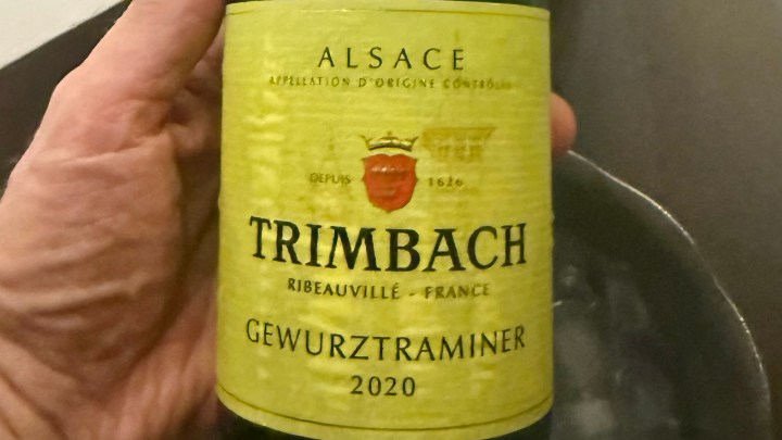 Close-up of a hand holding a bottle of Trimbach Gewurztraminer 2020 from Alsace, France, showing its label design.