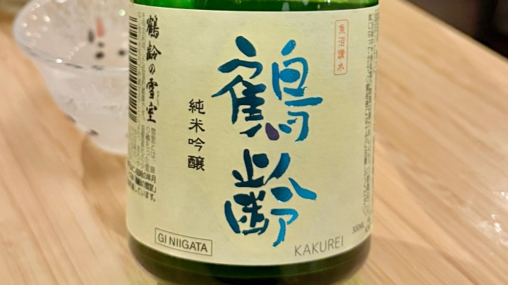 Close-up of a bottle of Kakurei Junmai Ginjo sake from Niigata, featuring elegant label design with Japanese characters.
