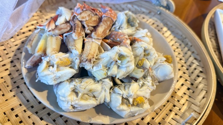A plate of fresh steamed crab legs, presented on a woven bamboo tray.