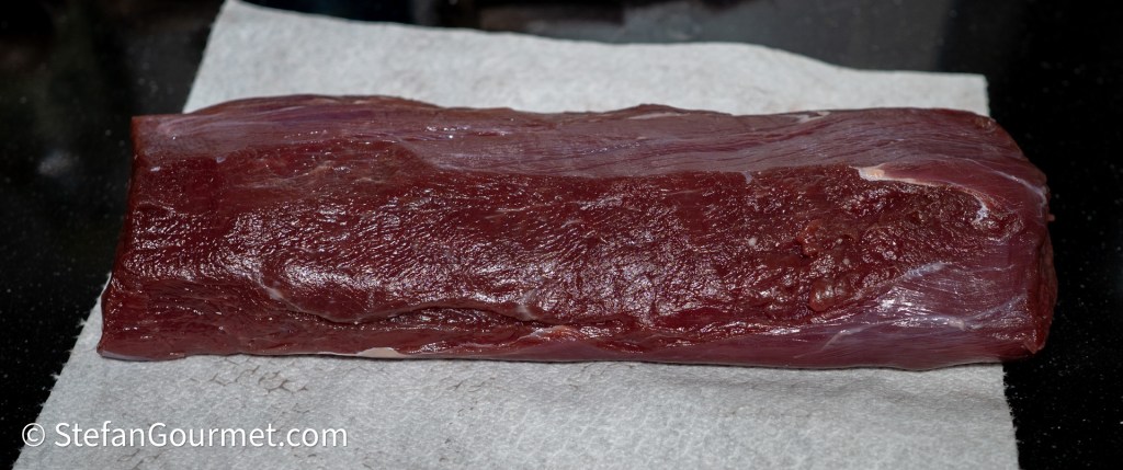 A piece of raw meat resting on a paper towel, displaying its rich red color and smooth texture.