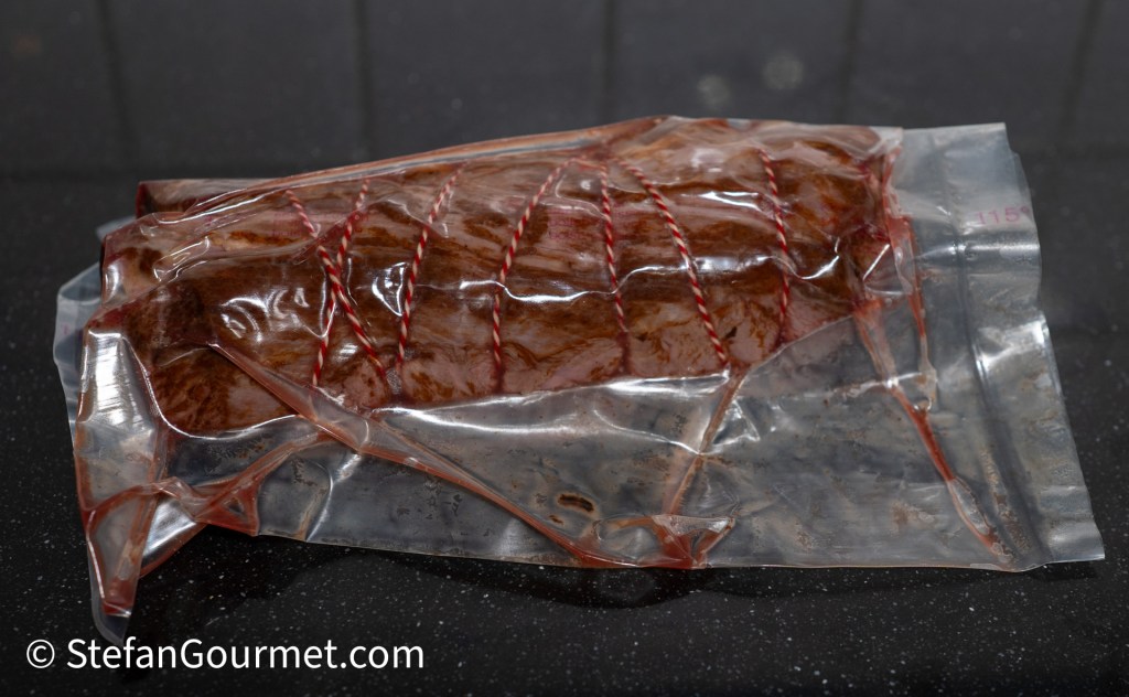 A sealed vacuum bag containing a piece of meat, showing red color and string tying.