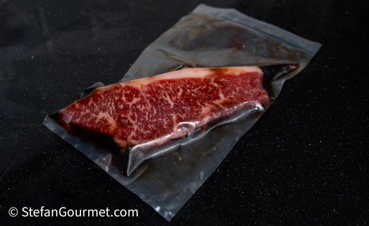 A vacuum-sealed piece of marbled beef, showcasing its rich texture and color.