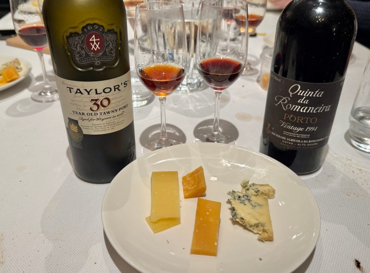 A bottle of Taylor's 30 Year Old Tawny Port alongside a bottle of Quinta da Romaneira Vintage Port from 1991, with three types of cheese and two glasses filled with Port wine.