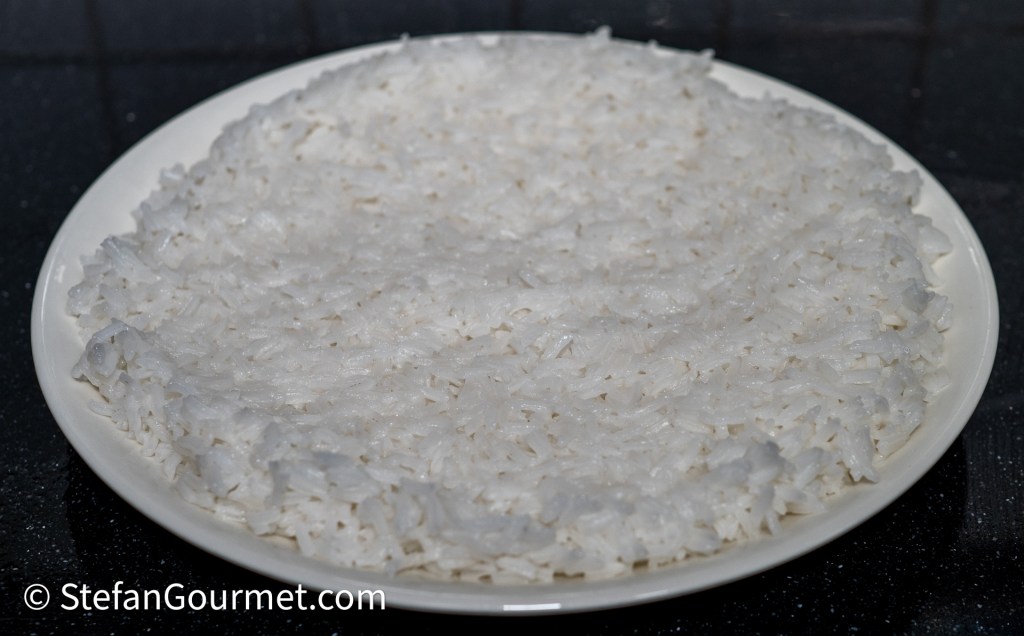 A round plate filled with fluffy, cooked white rice.