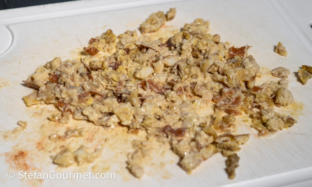 Chopped cooked meat on a cutting board, showing a mixture of textures and colors.