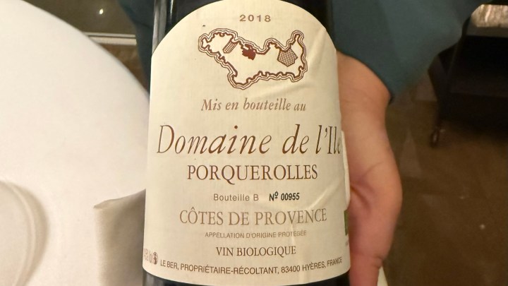 A close-up of a bottle label from Domaine de l'Ile, Porquerolles, featuring details about its vintage 2018, organic wine status, and Côtes de Provence designation.